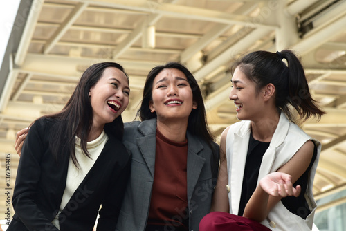 Business women sit down and talk together with smiling and laughing face in city background