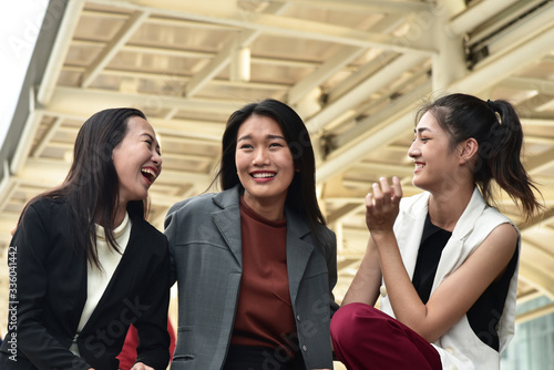 Business women sit down and talk together with smiling and laughing face in city background