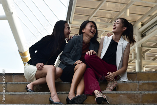 Business women sit down and talk together with smiling and laughing face in city background