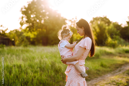 Bild auf Leinwand Mother and little daughter playing together in a summer park at sunset