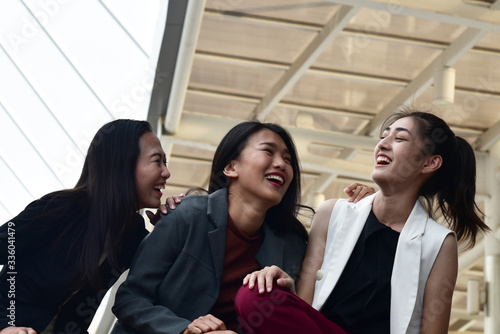 Business women sit down and talk together with smiling and laughing face in city background