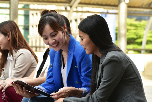 Smart young  business woman sitting down  using digital tablet for communication and presentaion with her team