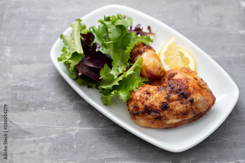 grilled chicken with lemon and salad on white dish grilled chicken with lemon and salad on white dish