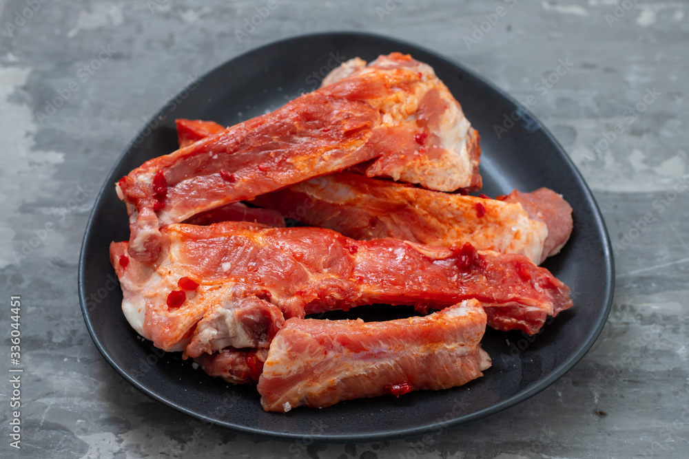 marinated meat on black dish on ceramic background