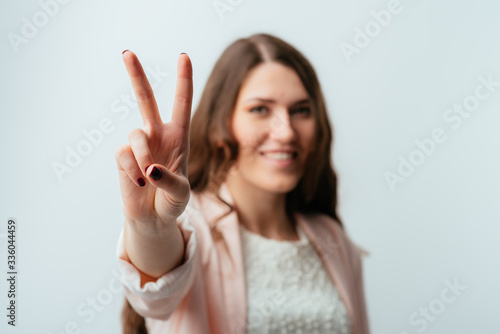long-haired beautiful brunette girl showing two fingers, positive or peace gesture, on white