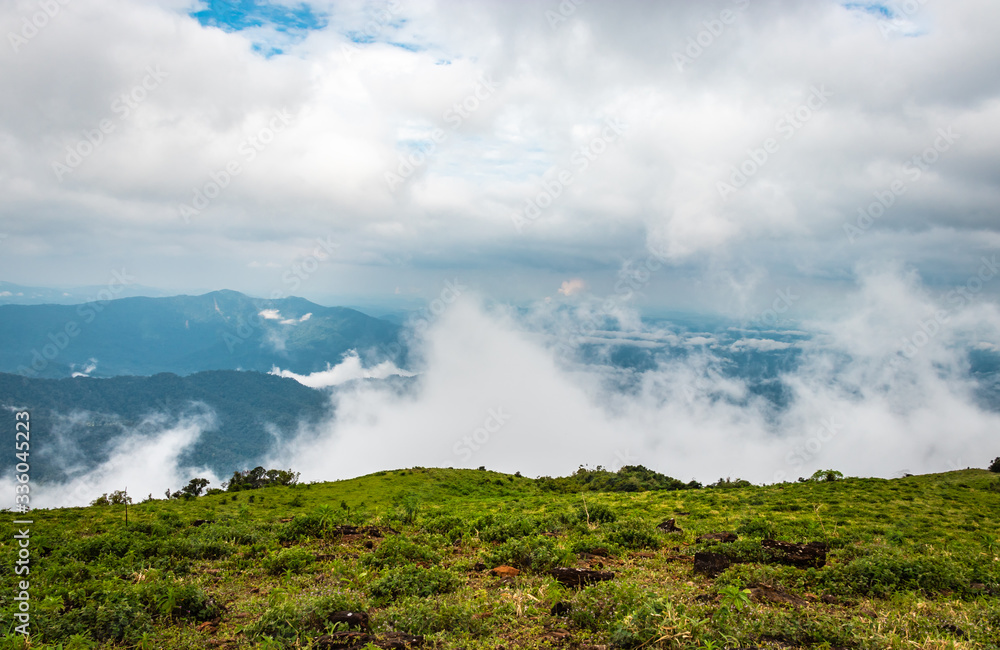 Cloud layers on mountain horizon with green grass