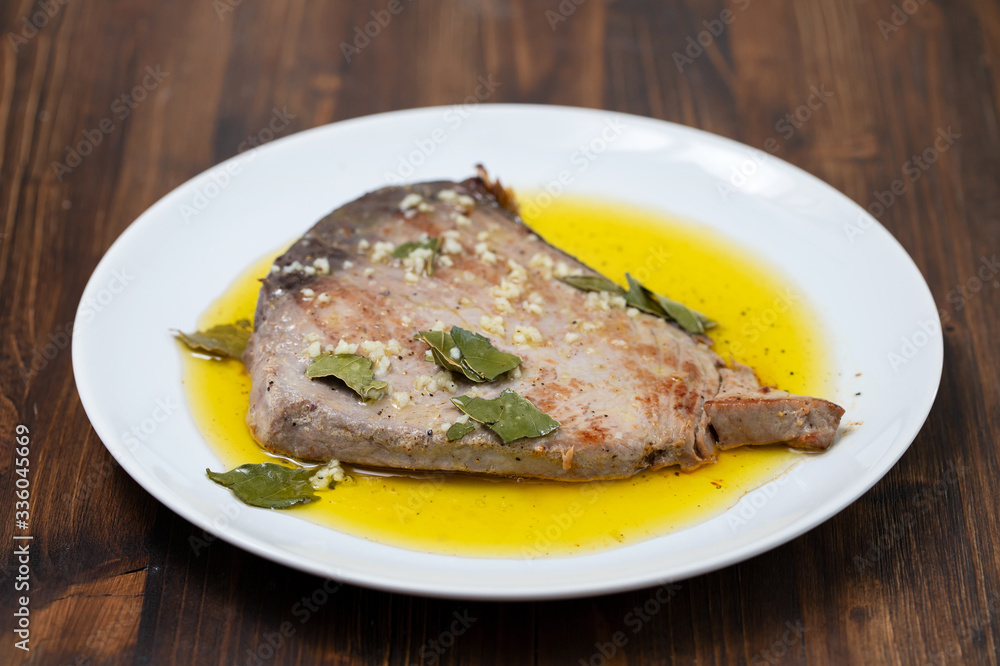fried tuna with garlic, bay leaf and olive oil on white plate fried tuna with garlic, bay leaf and olive oil on white plate