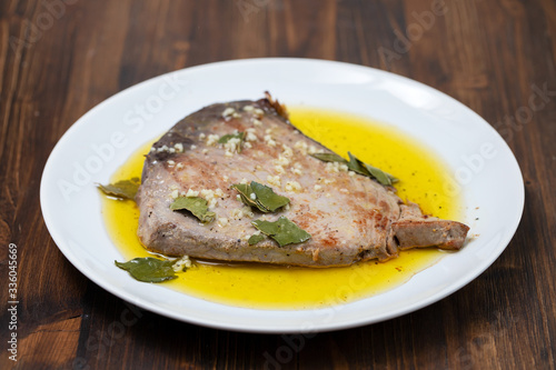 fried tuna with garlic, bay leaf and olive oil on white plate