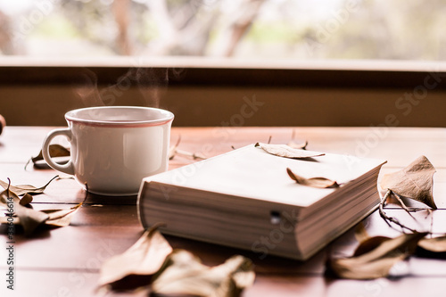 white book and coffee cup with leafs around