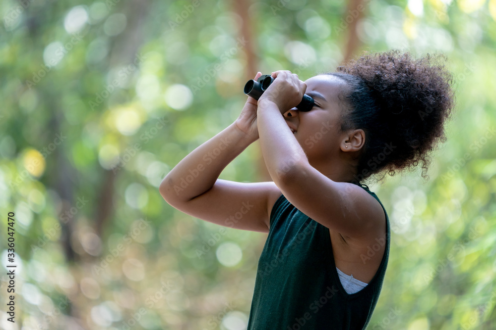 Little African American Girl with Binoculars during Hiking in Forest.