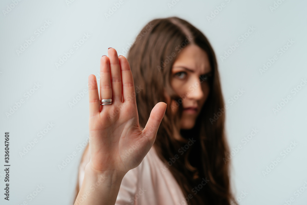 long-haired beautiful brunette girl shows stop, isolated on a white background long-haired beautiful brunette girl shows stop, isolated on a white background
