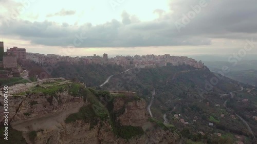 Aerial Dolly Zoom in to the City on the mountaintop. Enna in Sicily is a medieval city overlooked by old castle. Cloudy day with some sun shining through.