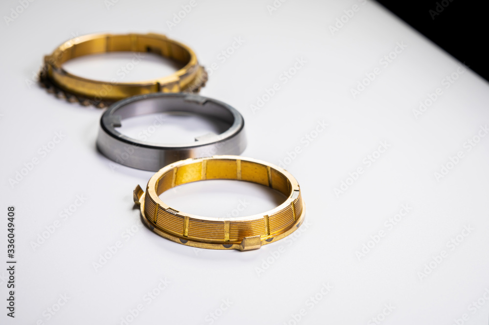 The individual elements of the transmission gear in the gearbox. A new set of synchronizers made of brass on a gray background. The individual elements of the transmission gear in the gearbox. A new set of synchronizers made of brass on a gray background.