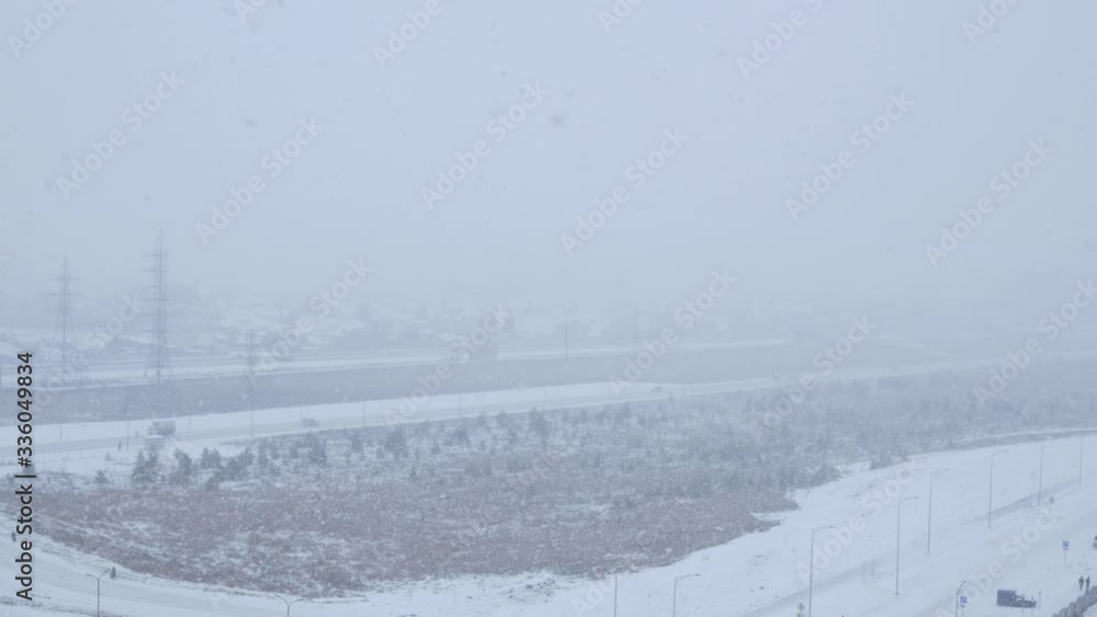 Snowstorm in the city, large flakes falling from the sky. Traffic on the roads due to poor visibility. Snowstorm in the city, large flakes falling from the sky. Traffic on the roads due to poor visibility.