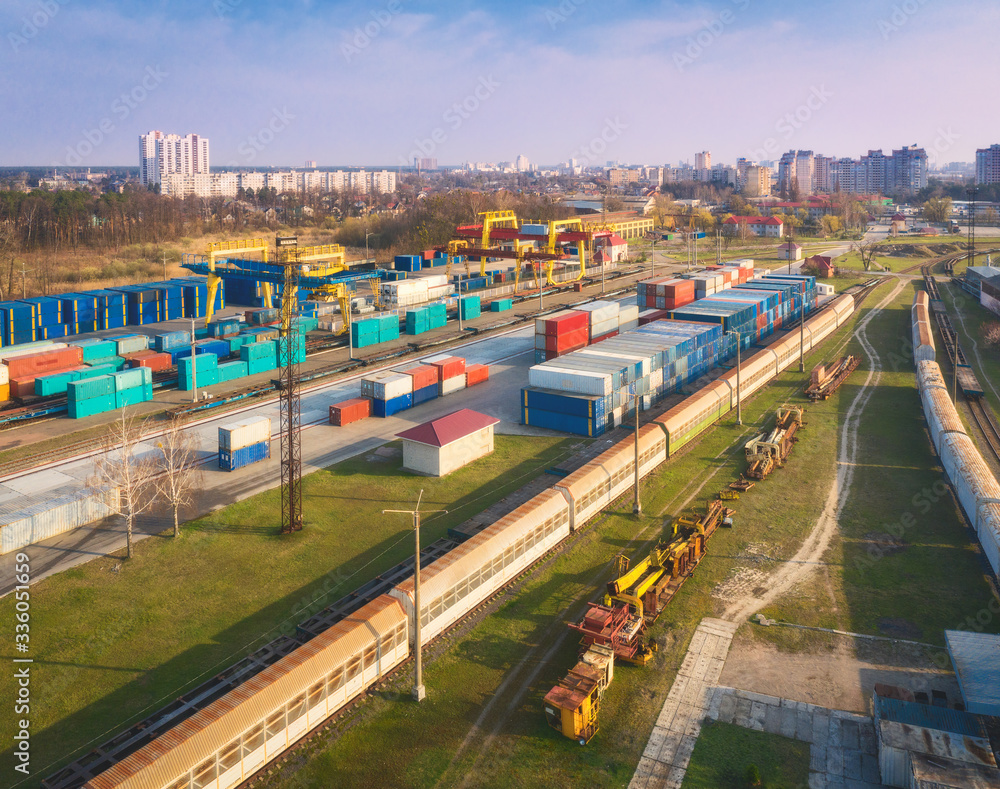 Aerial view of container loading and unloading at sunset. Top view of containers at logistics terminal for export and import, train, railroad. Business. Freight transportation containers on railway