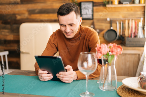 Young happy man online communication with digital tablet. Male using tablet computer and having online video chat.