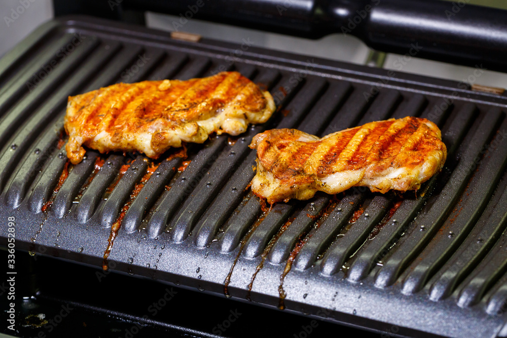 grilled chicken with spices on the electric grill in the home kitchen
