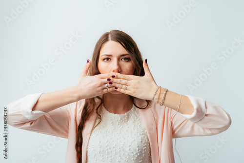 long-haired beautiful girl covers her mouth with her hands, isolated on white background