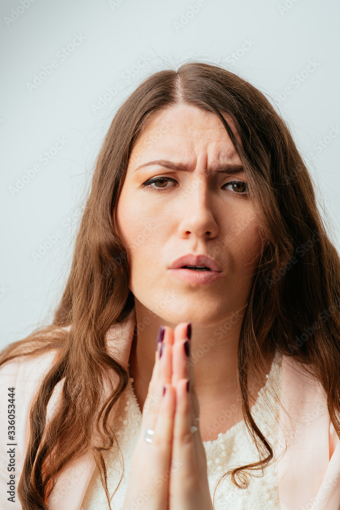 long-haired beautiful young brunette woman pleads with folded hands in front of him long-haired beautiful young brunette woman pleads with folded hands in front of him