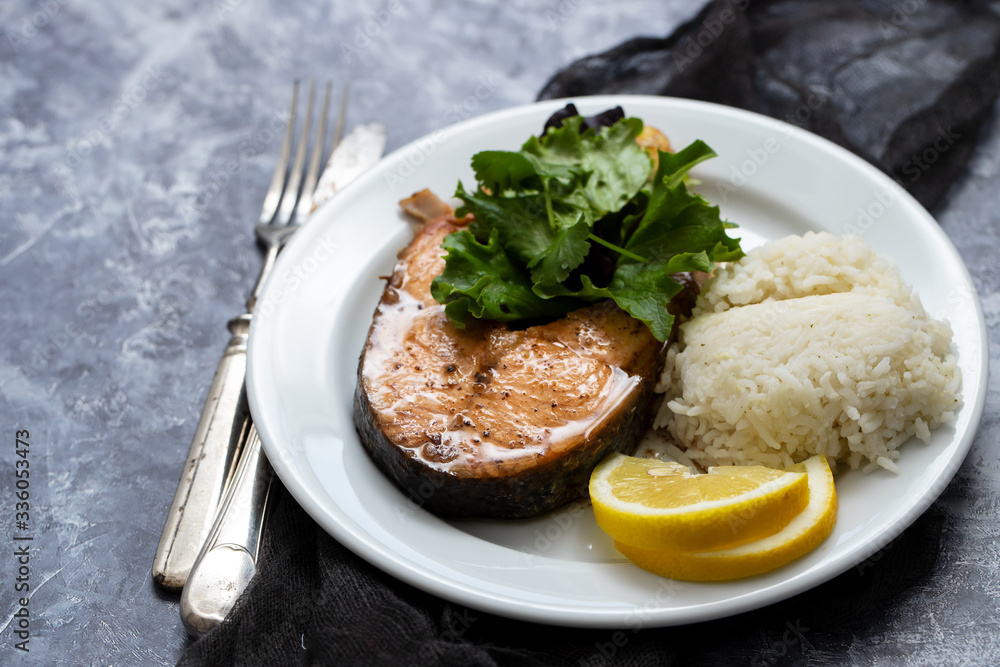 fried salmon with salad, lemon and boiled rice on white plate