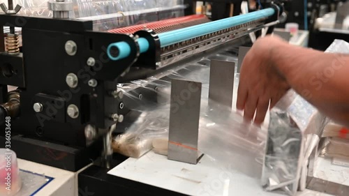 Closeup shows the hand of the staff picking the bag for packing and the plastic bag cutter is working to produce polypropylene bags in the concept of saving the world and the environment.