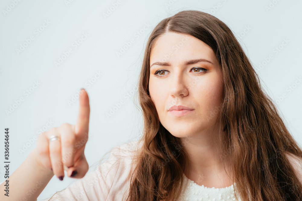 on a gray background young woman pointing at the board invisible on a gray background young woman pointing at the board invisible