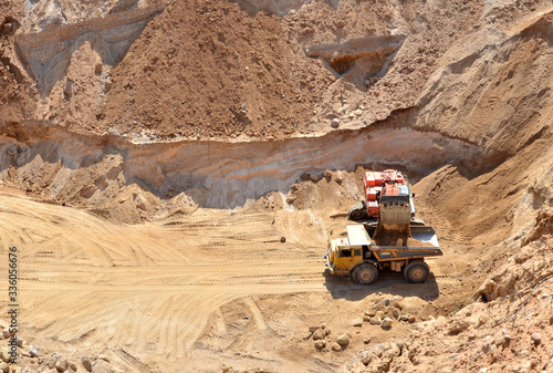 Excavator developing the sand on the opencast and loading it to the heavy dump truck. Processing of loose material in mining quarry. Drill, breaking, processing plant, crushing and screening - Image