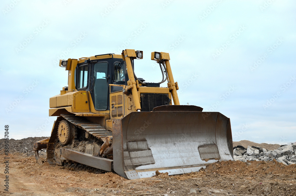 Dozer with bucket for pool excavation and utility trenching. Bulldozer during land clearing and foundation digging at construction site. Earth-moving equipment background