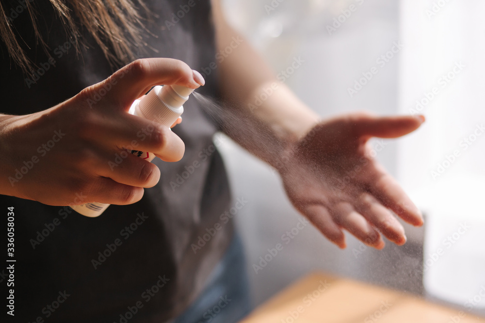 Close up woman hands using sanitizer spray, dispenser at home. Home isolation, quarantine. Coronavirus concept