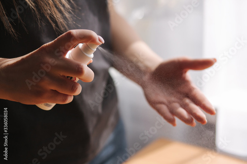 Close up woman hands using sanitizer spray  dispenser at home. Home isolation  quarantine. Coronavirus concept