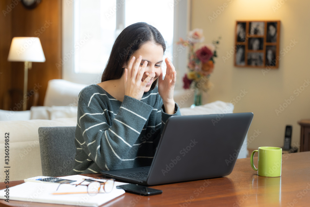 Surprised and smiling student with laptop at home Surprised and smiling student with laptop at home