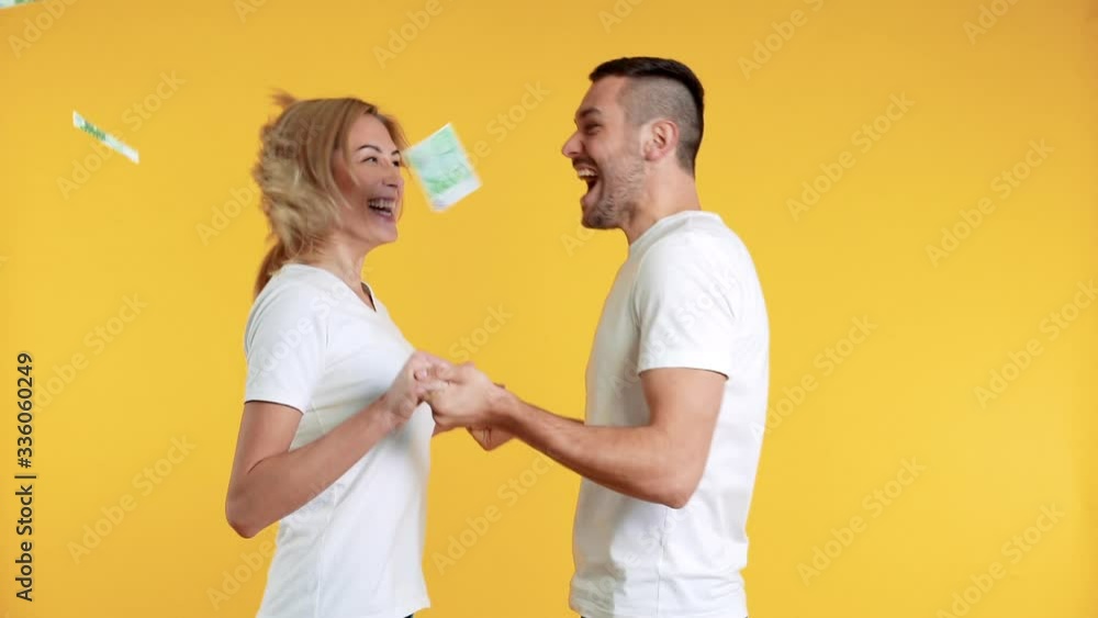 Surprised happy couple enjoying money rain banknotes falling down. Success, business, and fortune concept. Slow motion Surprised happy couple enjoying money rain banknotes falling down. Success, business, and fortune concept. Slow motion