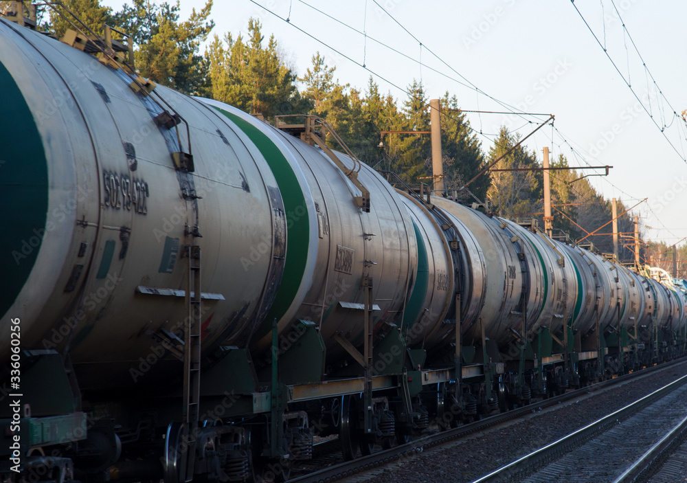 Freight train with petroleum tank cars on railroad. Rail cars carry oil and ethanol. Railway logistics explosive cargo. Transportation of methanol, crude and gas.Petrochemical tank cars
