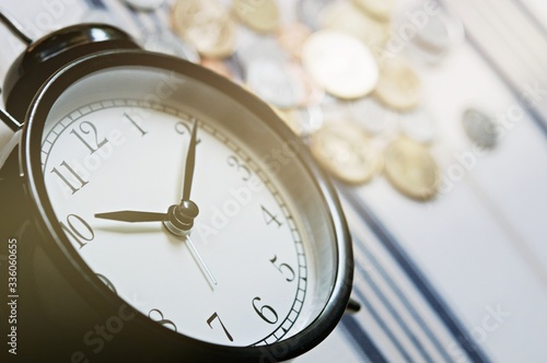 Vintage alarm clock and group of growing coins placed on the floor, selective focus and shallow depth of field, investment concept. growing on coin, Business Finance and Save Money.