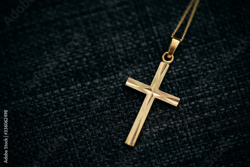 goldene Kette mit Kreuz-Anhänger vor schwarzem Grund