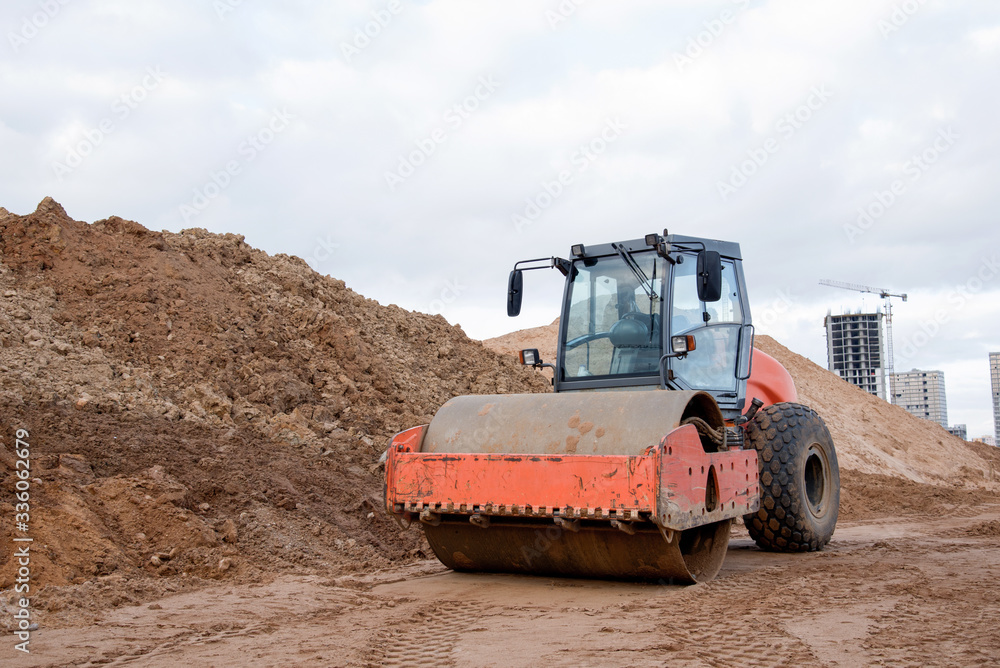 Soil Compactor at construction site. Vibration single-cylinder road roller for leveling soil, gravel, concrete, or asphalt in the construction of roads and foundation. Road Construction Equipment Soil Compactor at construction site. Vibration single-cylinder road roller for leveling soil, gravel, concrete, or asphalt in the construction of roads and foundation. Road Construction Equipment