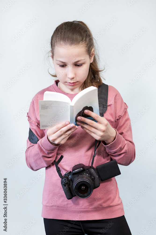 Fototapeta premium Teen age girl reading service manual book for dlsr camera, beginner in learning photography, a grey background