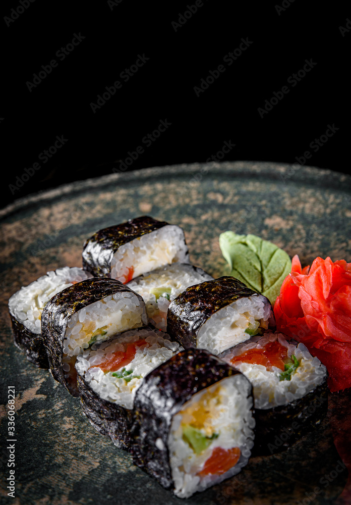 sushi roll with salmon, cucumber, cream cheese, rice in plate on black wooden table background sushi roll with salmon, cucumber, cream cheese, rice in plate on black wooden table background
