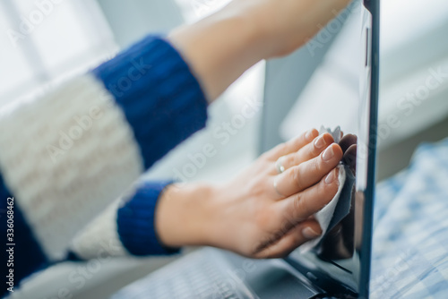 people, housework, electronics and housekeeping concept - close up of woman hand cleaning laptop computer screen with cloth