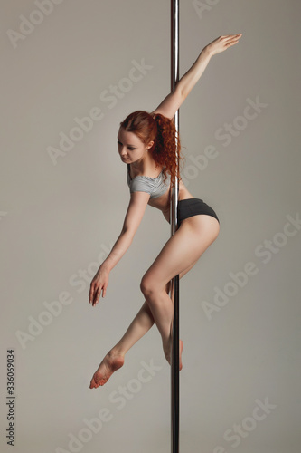 Beautiful sports girl doing acrobatics on a pole