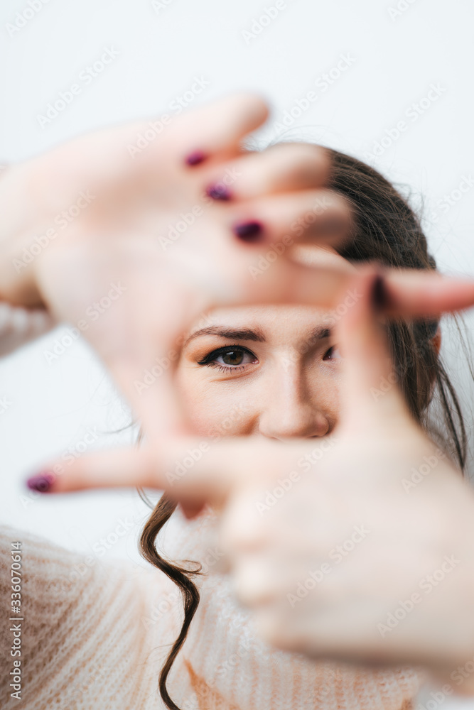 Fototapeta premium brunette girl doing camera hands and fingers on a white background