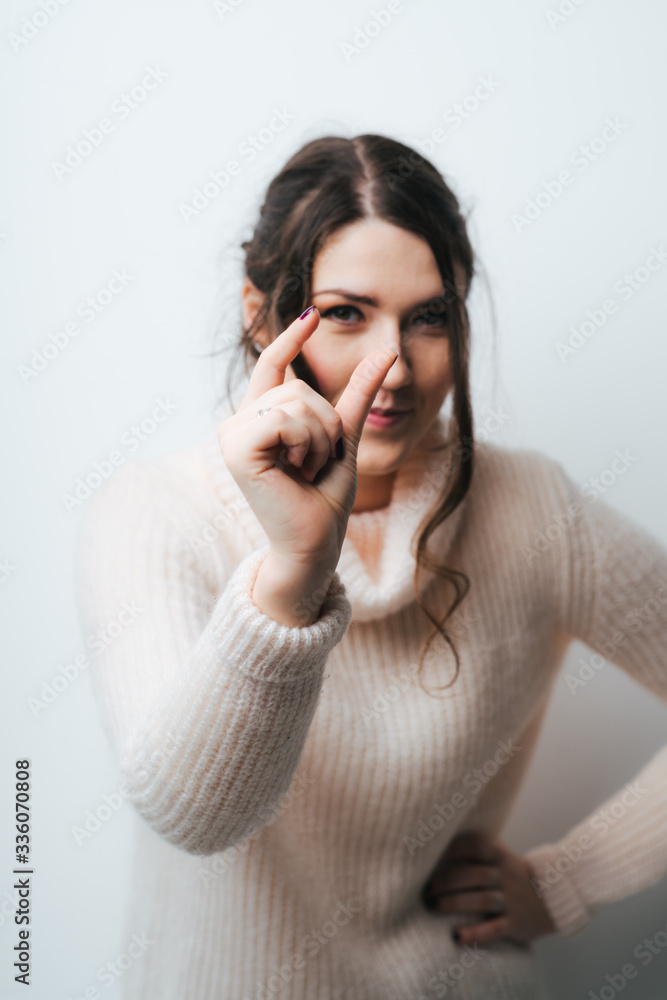 Brunette girl shows something very small on a white background Brunette girl shows something very small on a white background