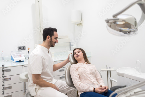 Portrait of a bearded dentist male explaining procedure to a female patient