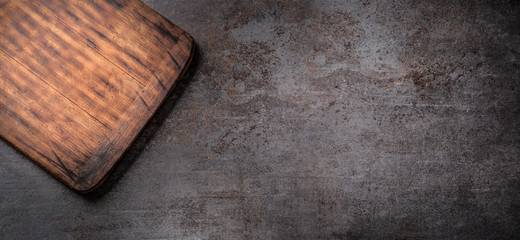 Dark metallic surface with a rectangular empty wooden cutting board in top left corner