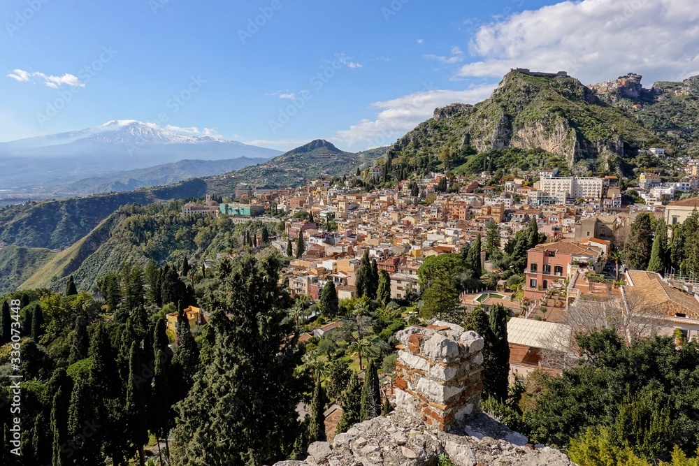 Cityscape of the Taormina city in Sicily, Italy and mountains with Etna volcano in background
