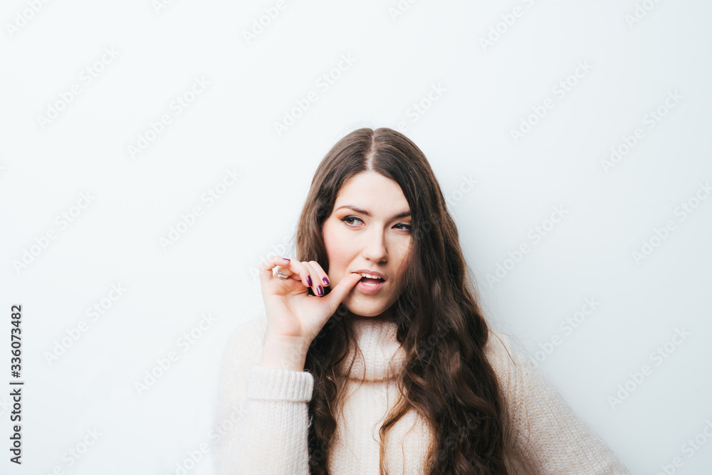 beautiful long-haired girl bites his nails on a white background beautiful long-haired girl bites his nails on a white background