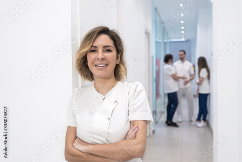 Portrait of female doctor standing with arms crossed in corridor