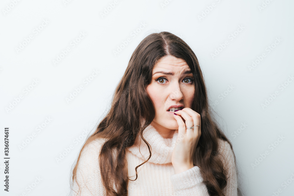 on a white background young girl with long hair chews nails on a white background young girl with long hair chews nails