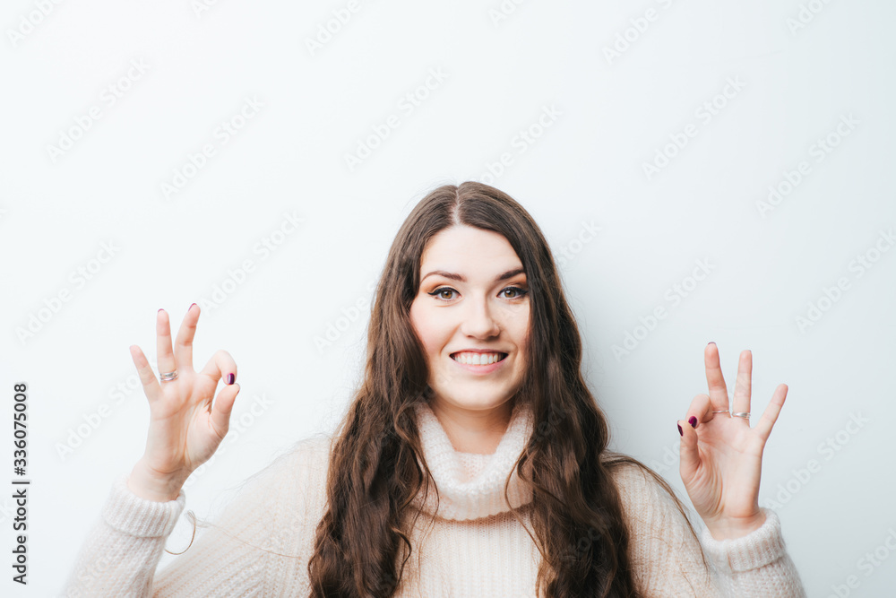 on a white background young girl with long hair shows OK on a white background young girl with long hair shows OK