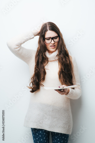 on a white background young girl in glasses with long hair reading a notebook